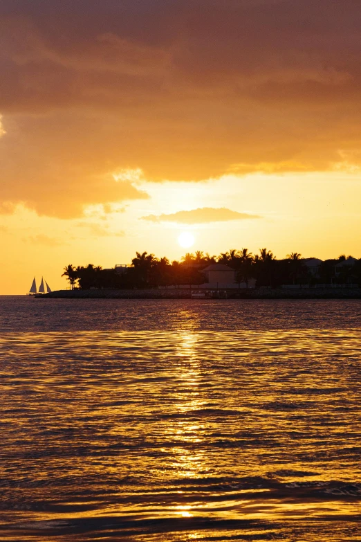 an island on the water at sunset with boats coming in