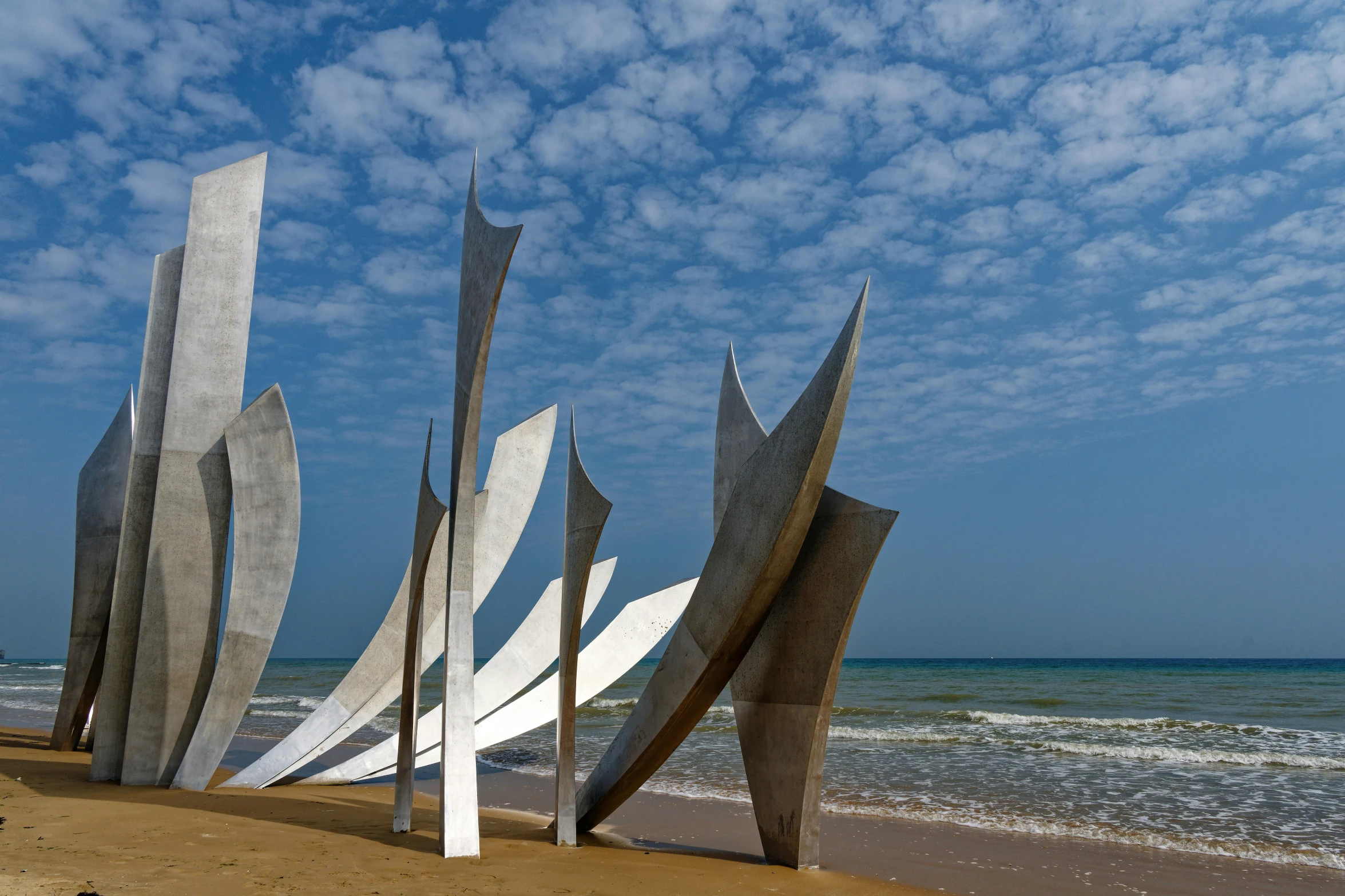 two sculptures in front of the water near a beach