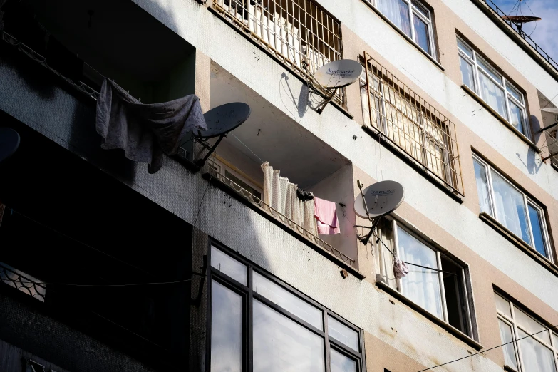 a building with multiple satellite devices hanging out of it's windows