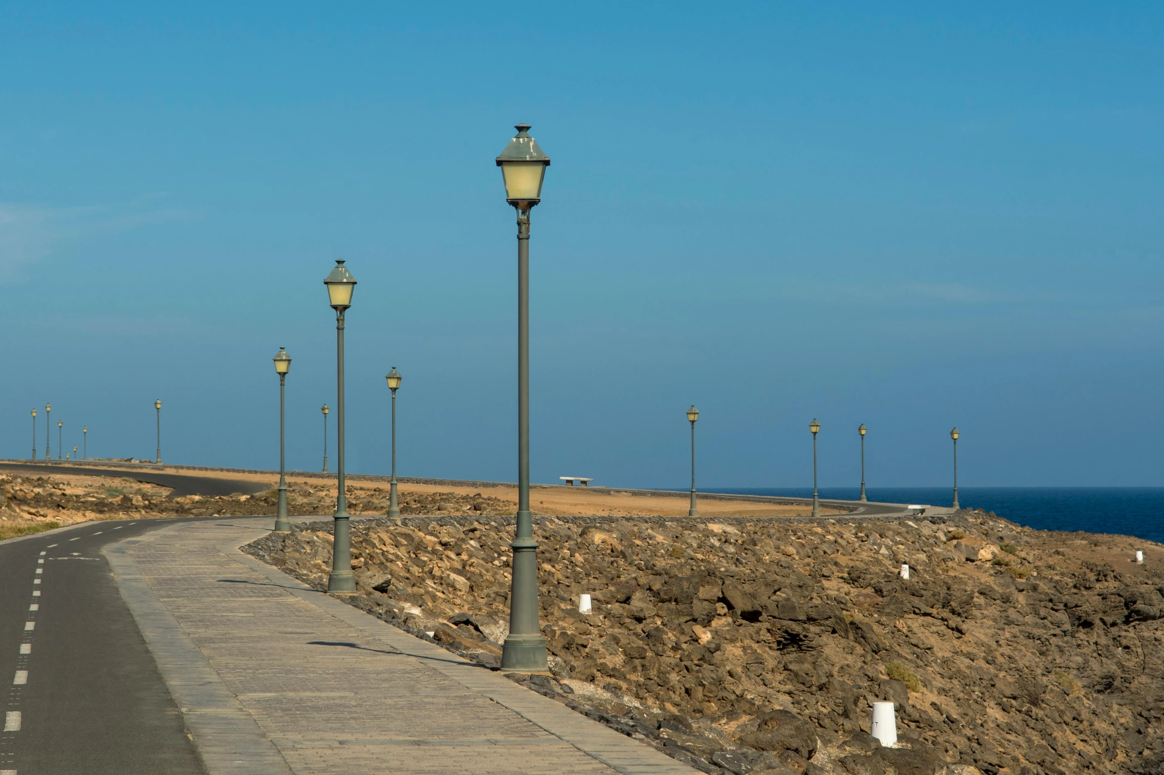 an empty road next to the ocean during the day