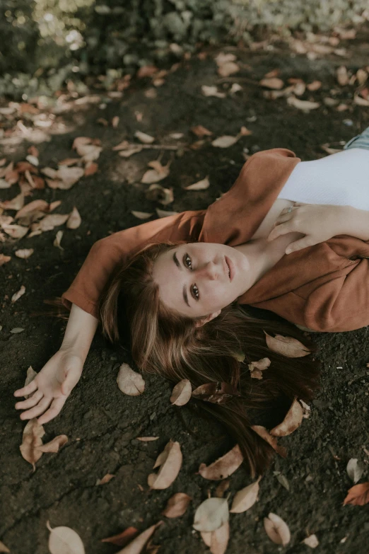 a woman laying in a park on top of leaves