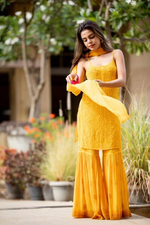 a woman standing on the street in a yellow dress