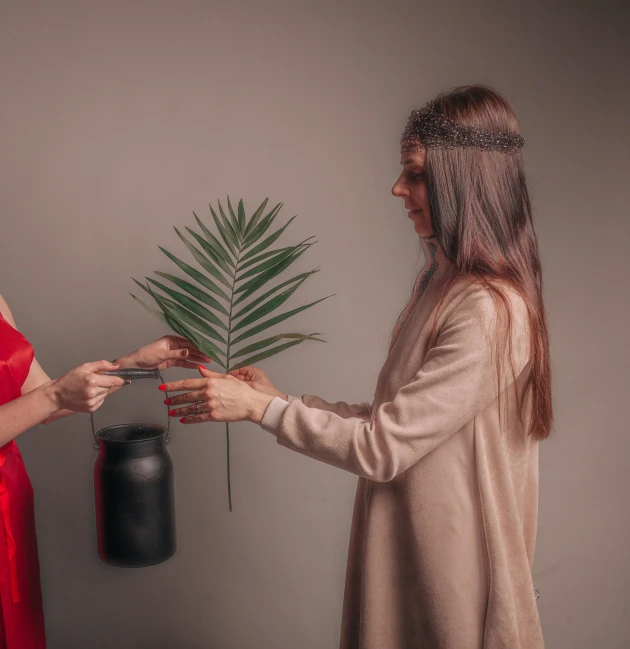 two women in costumes touching hands next to a plant