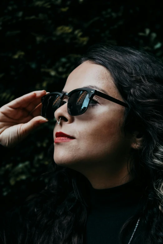 the woman in sunglasses is looking up at the trees