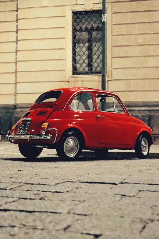 an old red car parked on a street next to a building