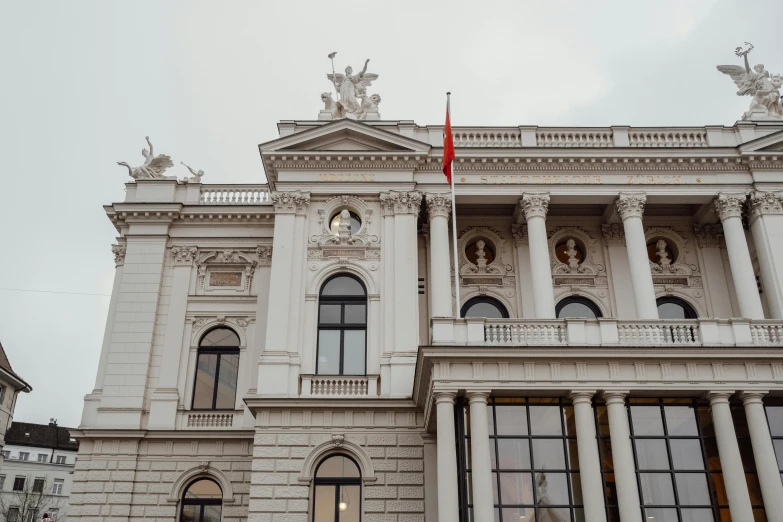 two red flags are on a pole outside a large building