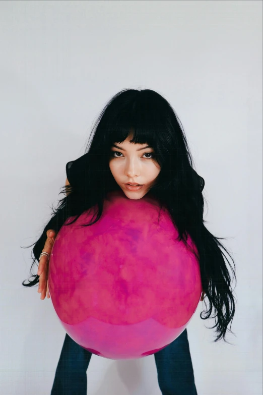 an asian woman holding a pink balloon