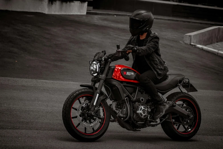 a man sitting on a red and black motorcycle