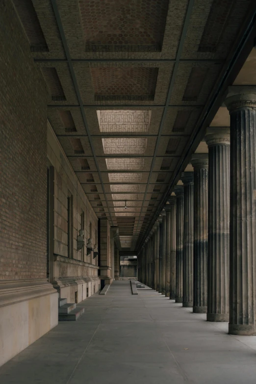 long row of pillars in concrete building next to walkway