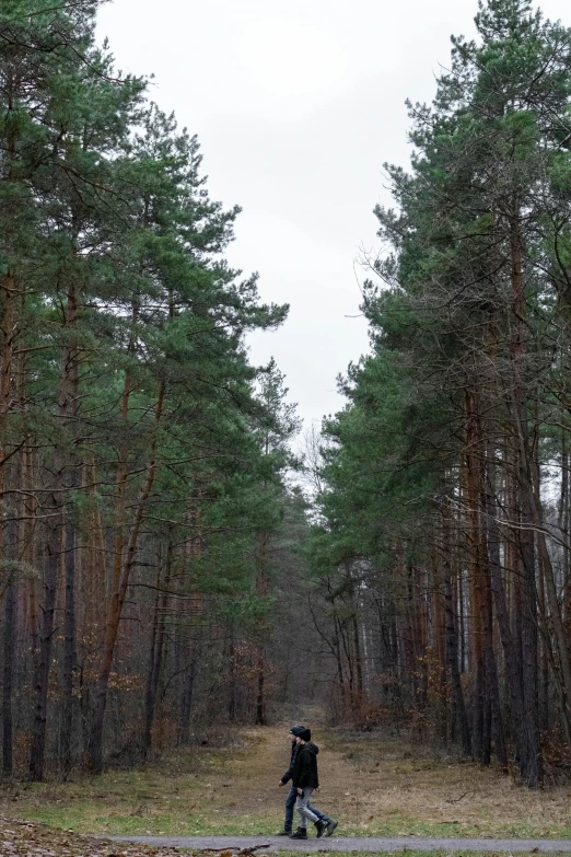 there is a man walking down the road near some trees