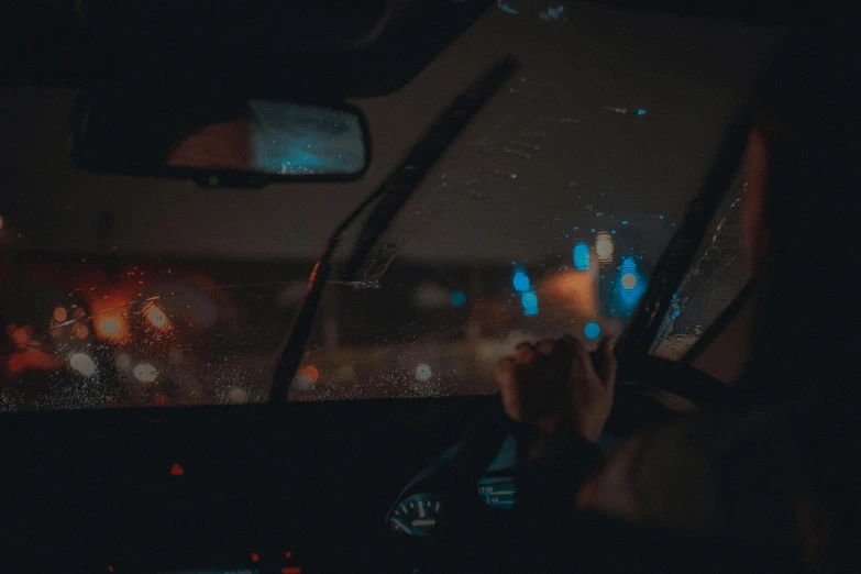 a person is taking a picture in the rear seat of a car with lights from behind it