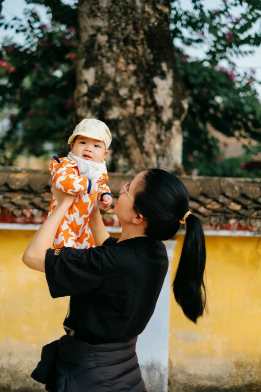 woman holds baby up to her ears while outside