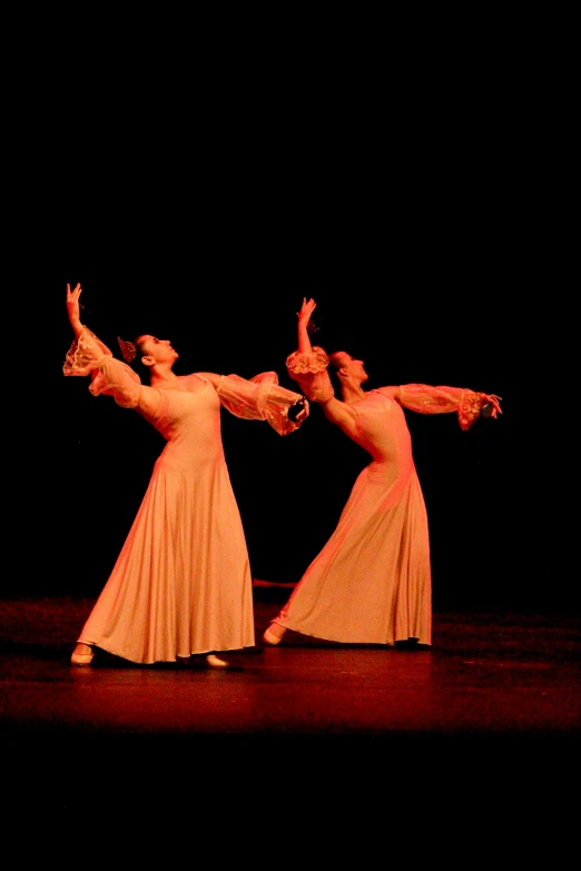 two women are dancing on stage wearing orange skirts