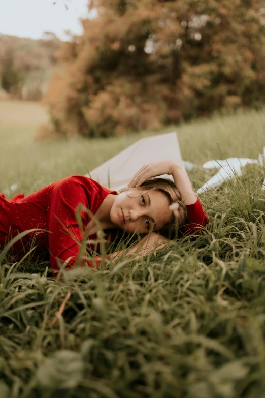 a woman in a red shirt lies on grass