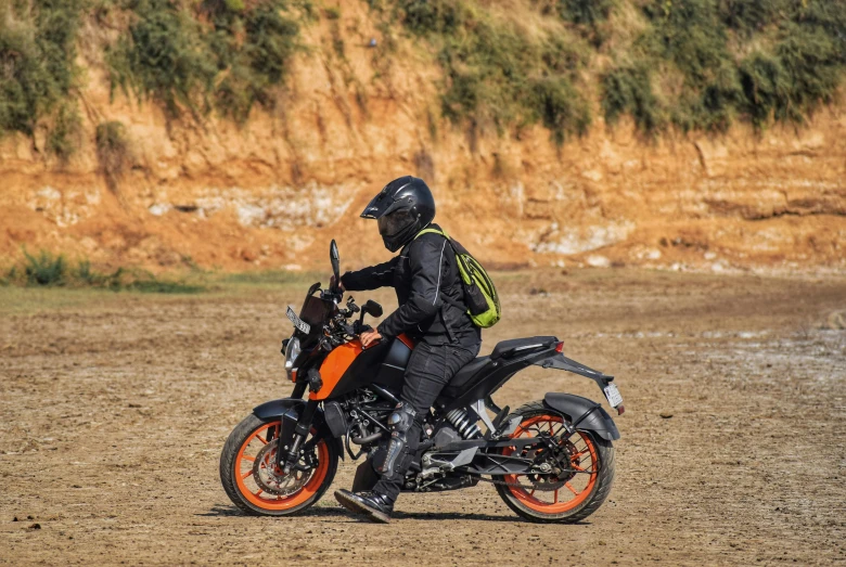 a person on an orange motorcycle with a dirt background