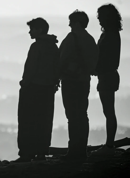 the silhouettes of three people stand on a rocky ledge