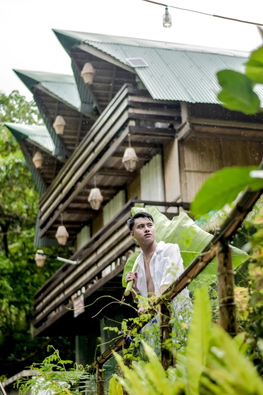 an asian man is posing outside of a house