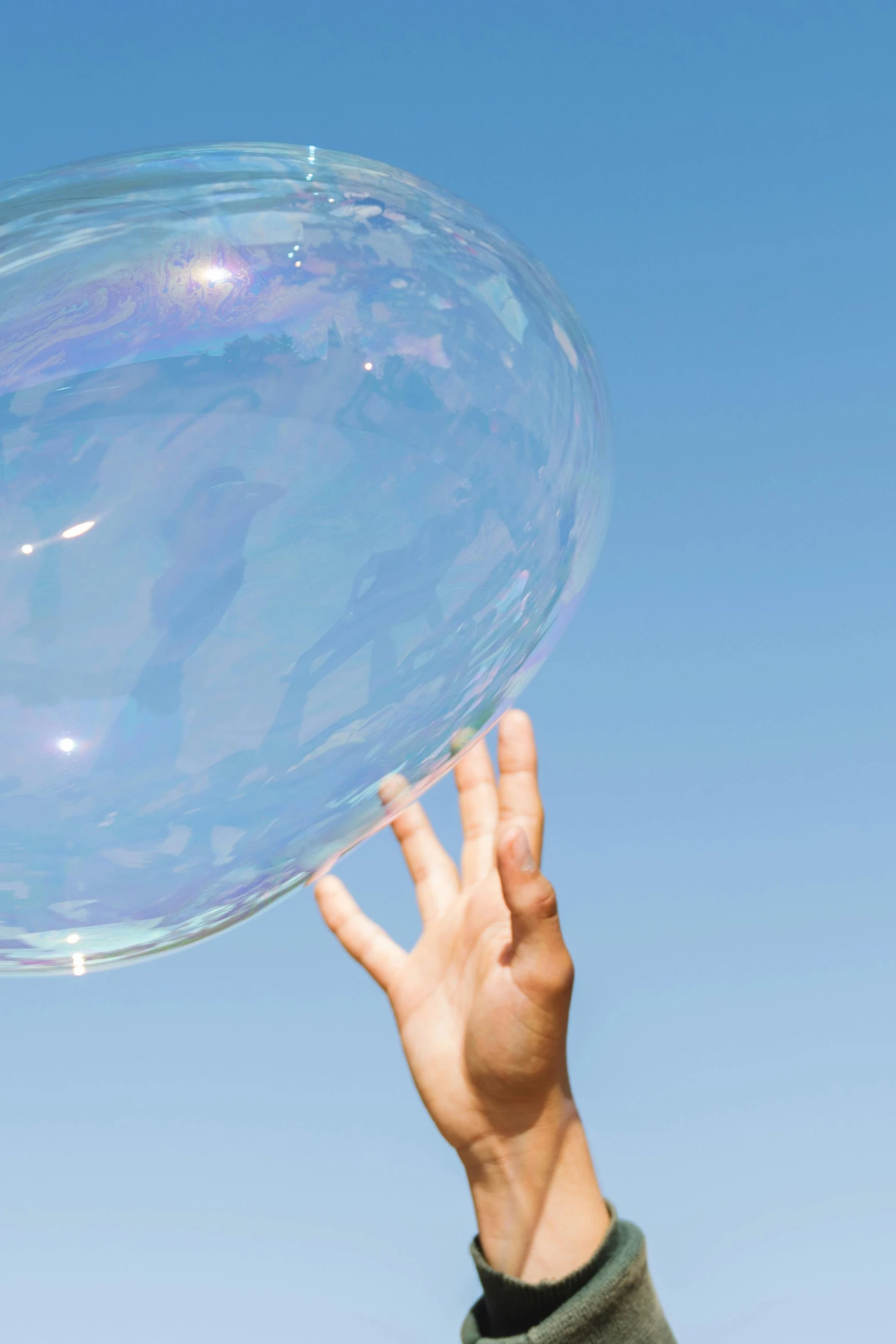 a man's hand reaches up for a bubble