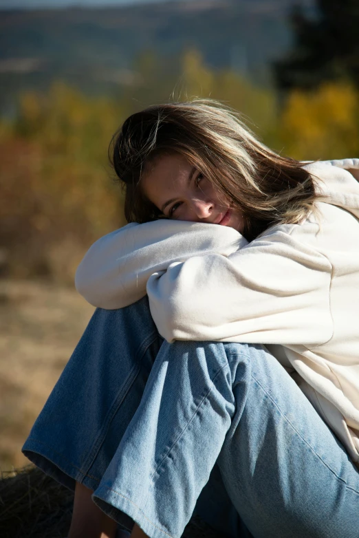 a close up of a person sitting in front of a tree