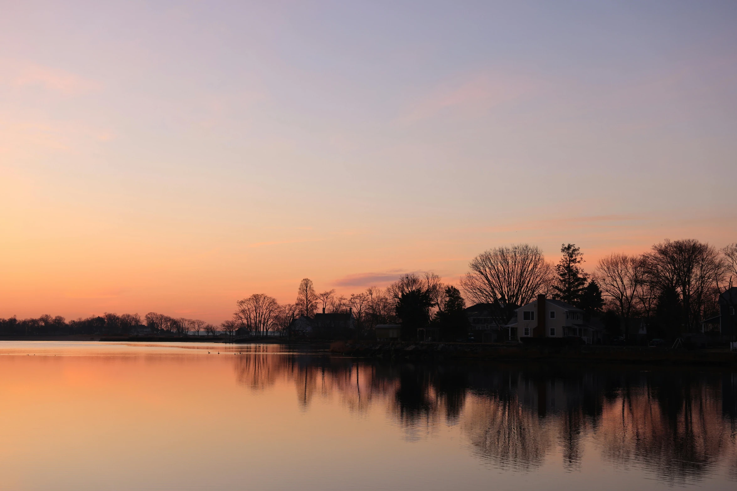 a lake with a house and trees in it during the sunset