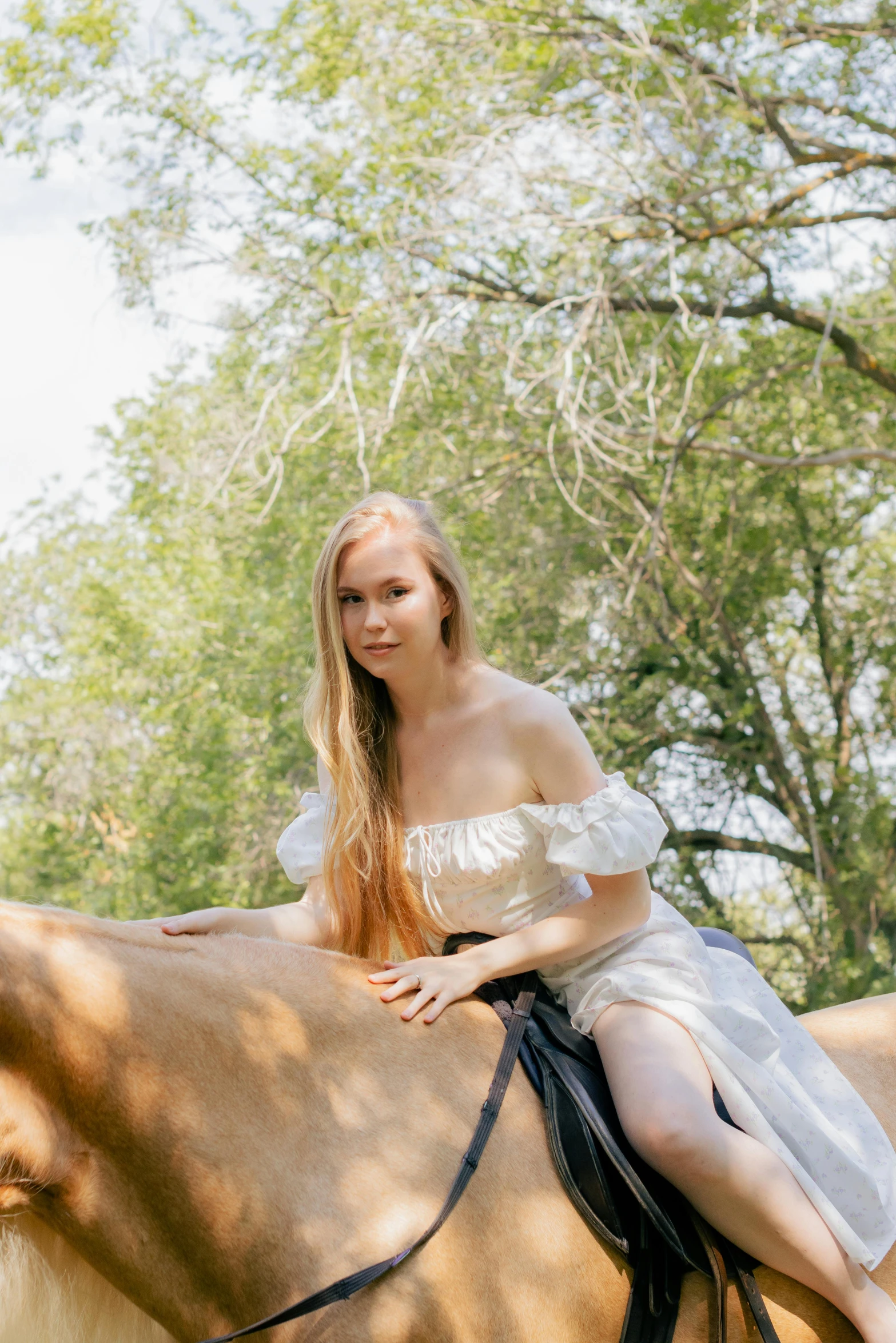 a young woman in white sitting on the horse