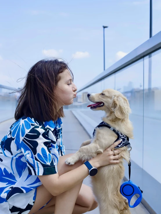 a woman is holding her dog and she is wearing a blue shirt