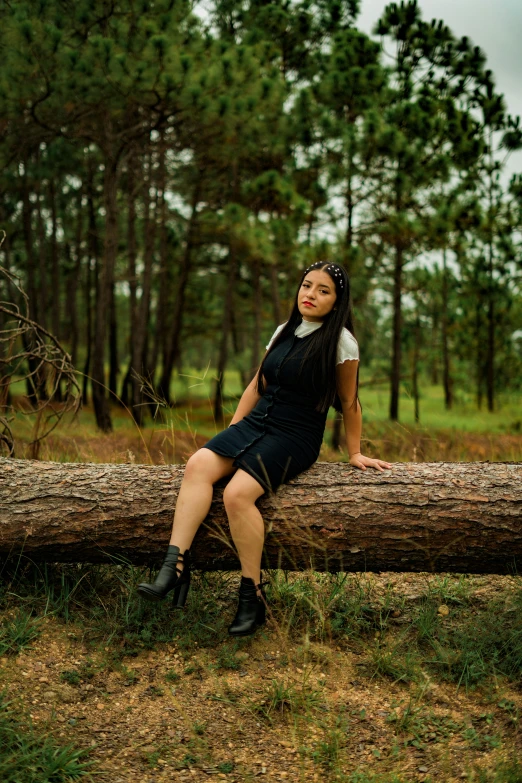 a beautiful young lady sitting on a log posing for a po