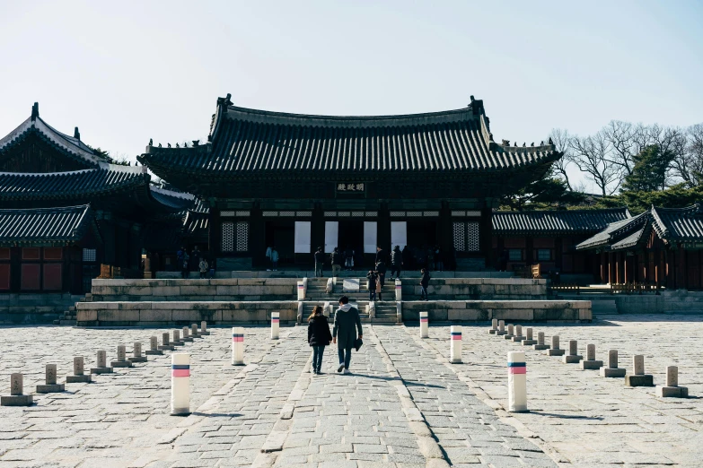 two people walking toward the entrance to a chinese style building