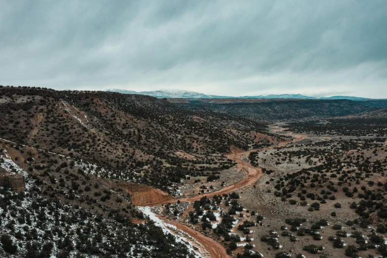 an aerial view of a dirt road with trees and mountains in the background