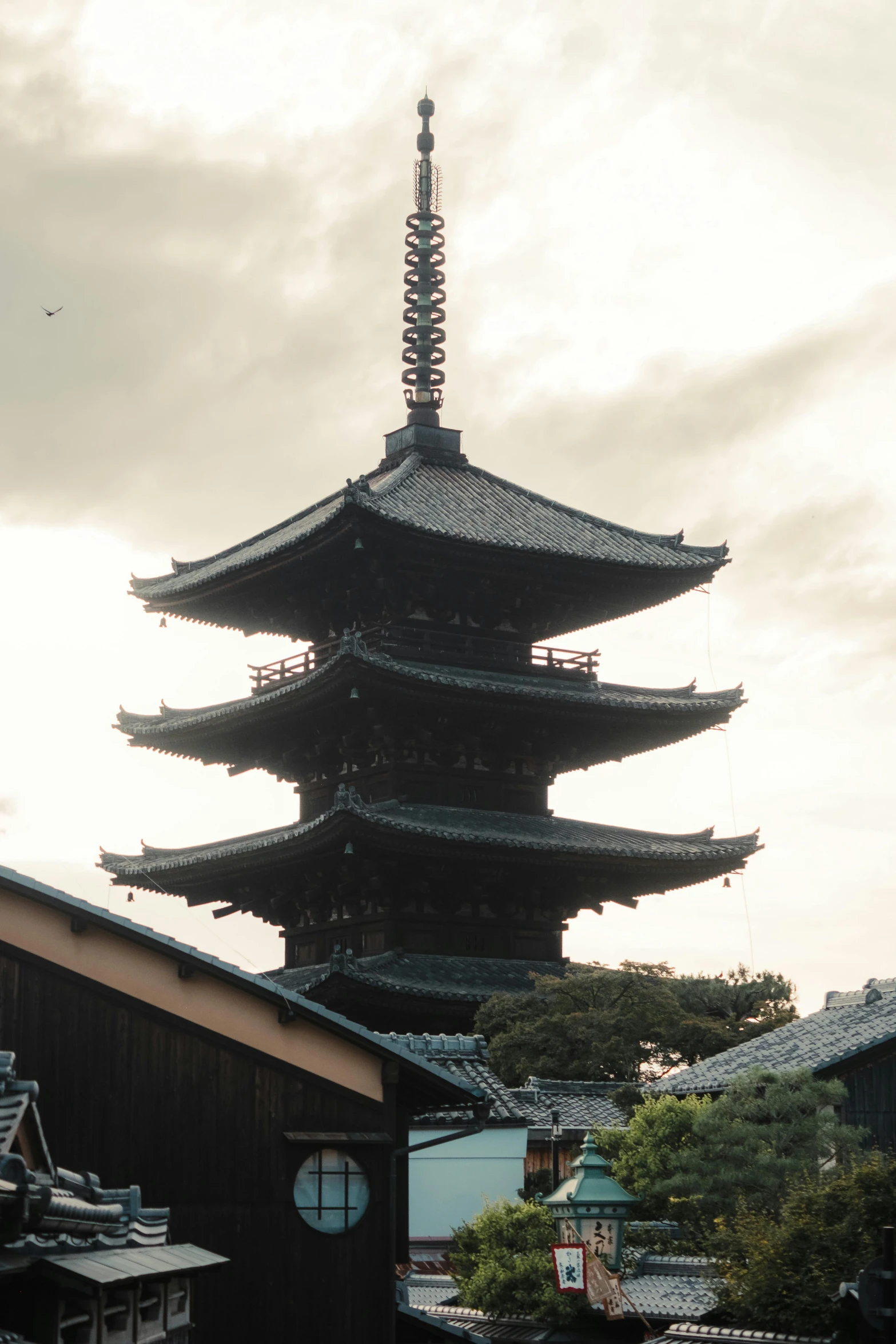 a tall pagoda towering over a town and surrounded by trees