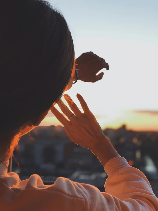 a woman holding her hand up against the sky