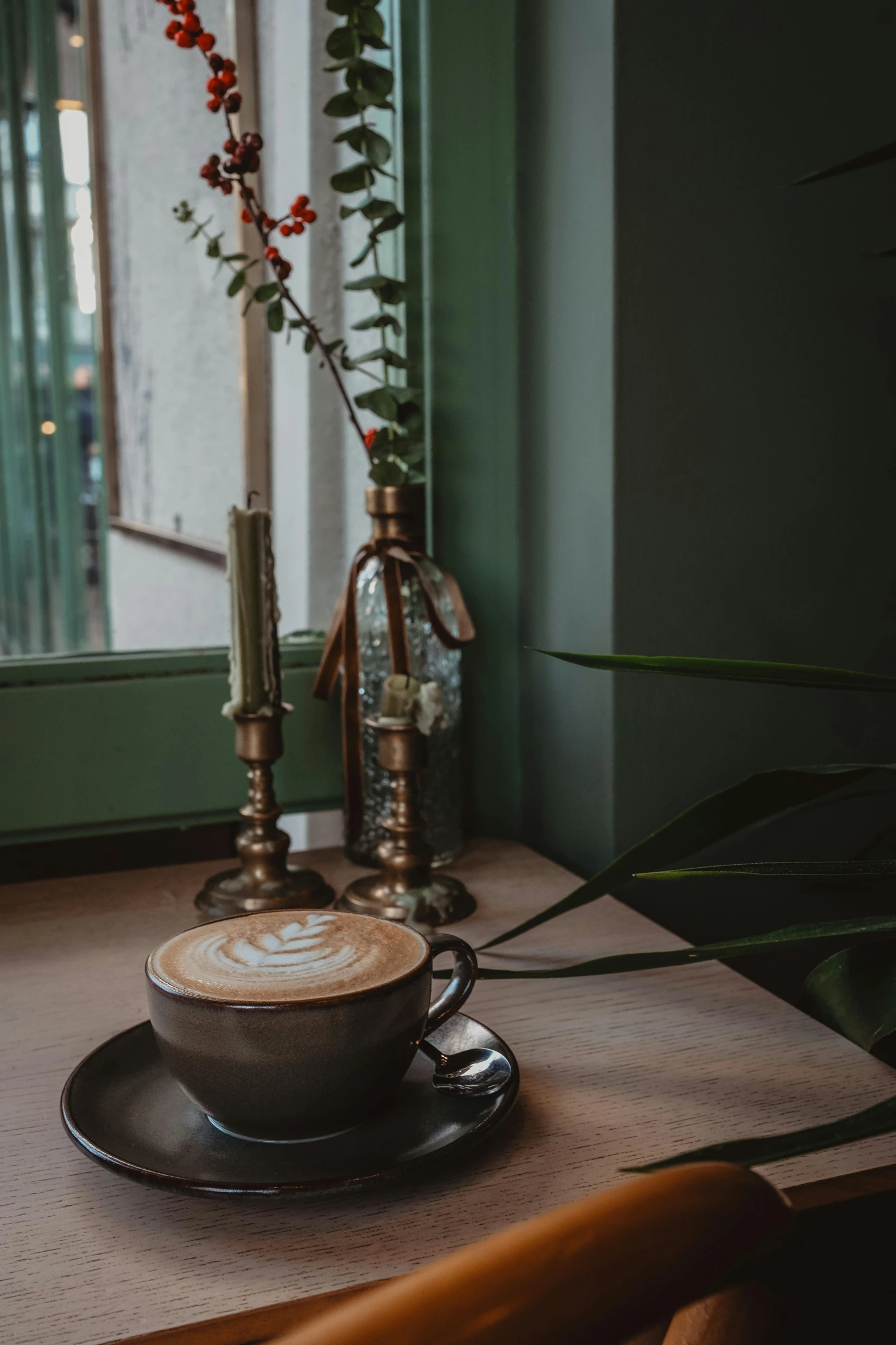 an empty cup of coffee sits on a wooden table in a room with green walls and windows