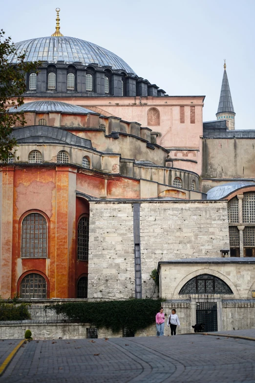 two people are walking past a large building