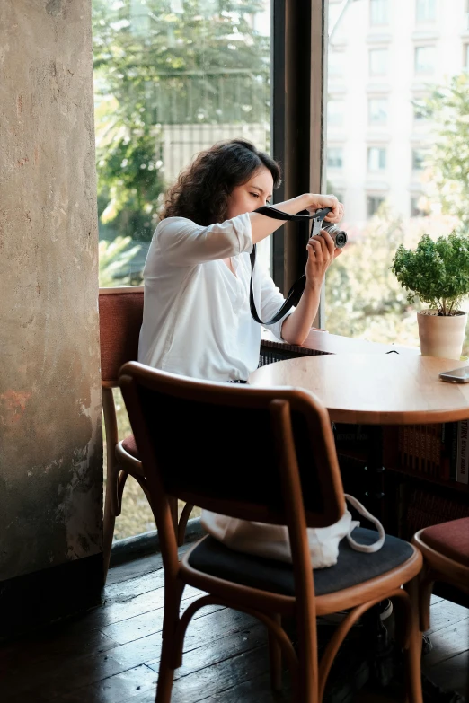 a woman taking a po of a plant sitting on a table