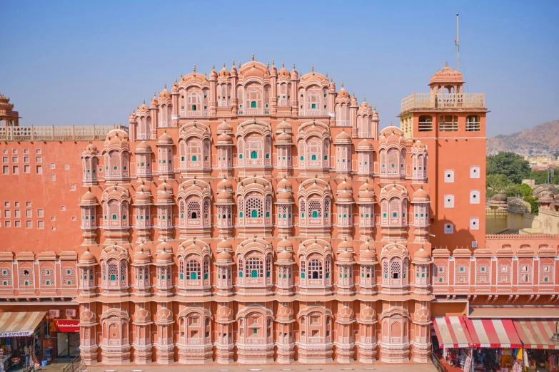 pink building with intricate architecture and people sitting on the sidewalk