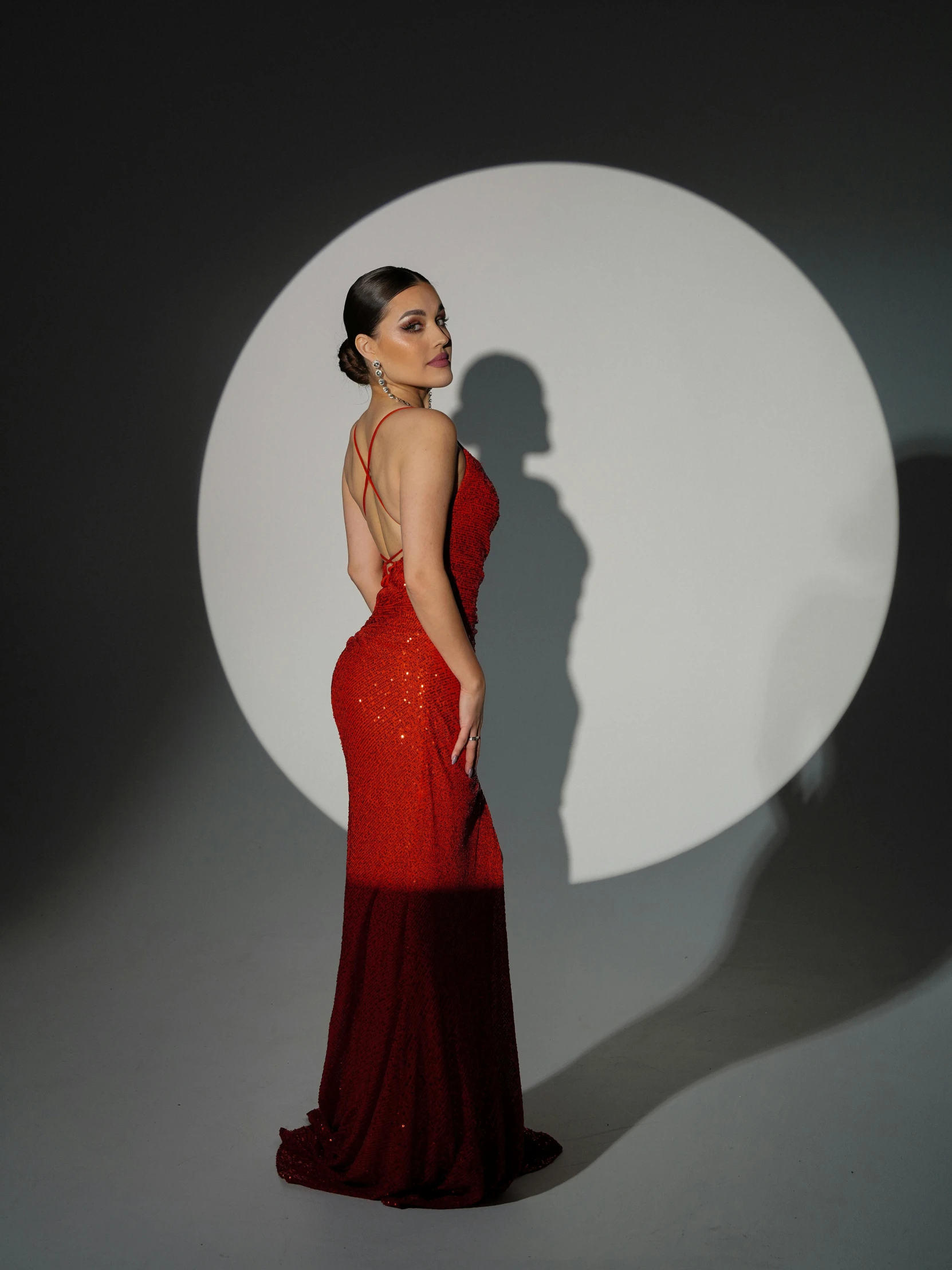 a woman in red dress standing against a wall