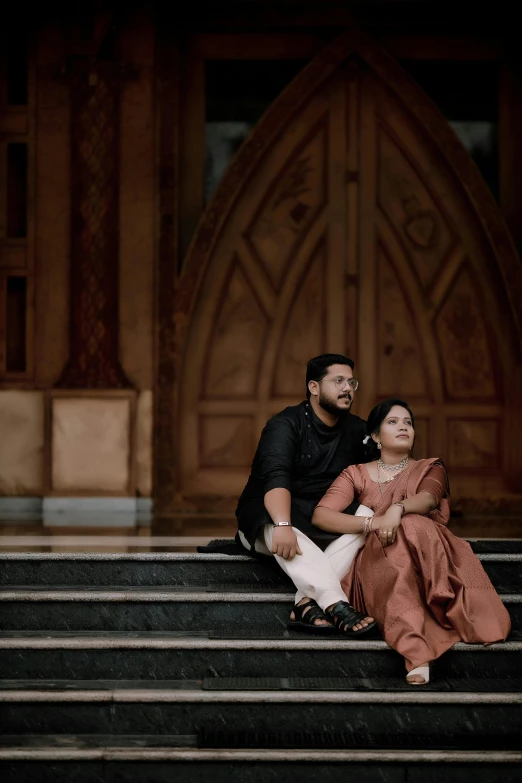 an image of a man and a woman sitting on stairs in front of a church