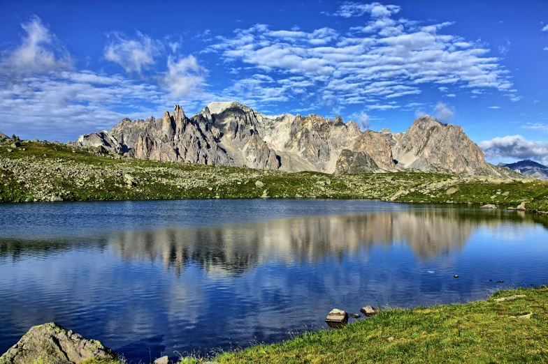 a lake on a grassy hill and mountains