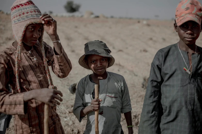 three women with a stick on their shoulder, wearing hats