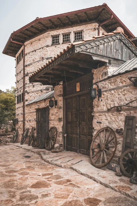 a rustic looking building that has a wagon and wheel in front