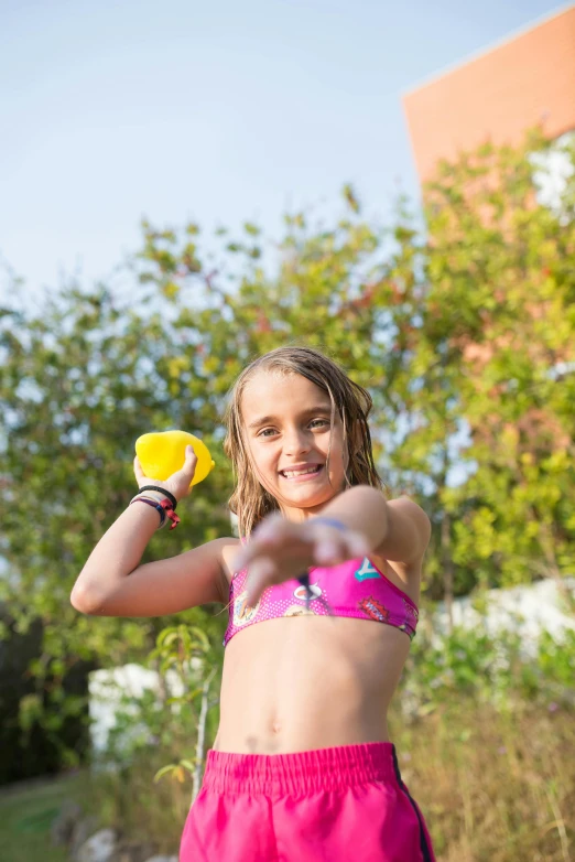 a girl holding a frisbee and yellow ball