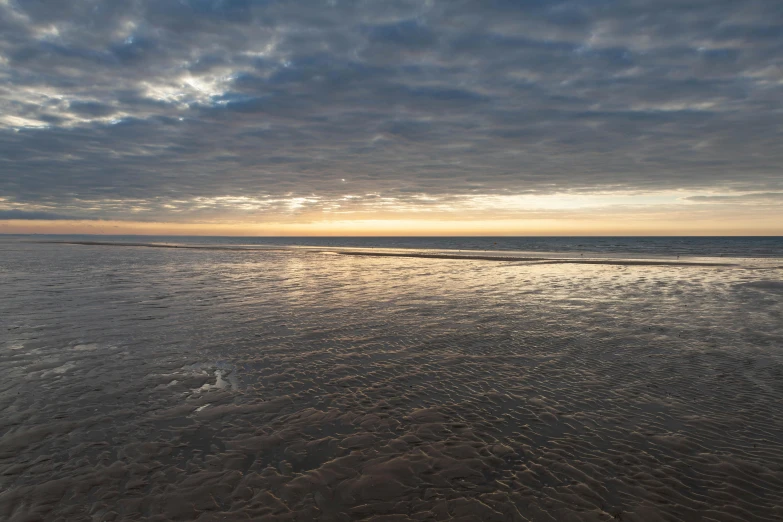 the sky is very cloudy at sunset on the beach