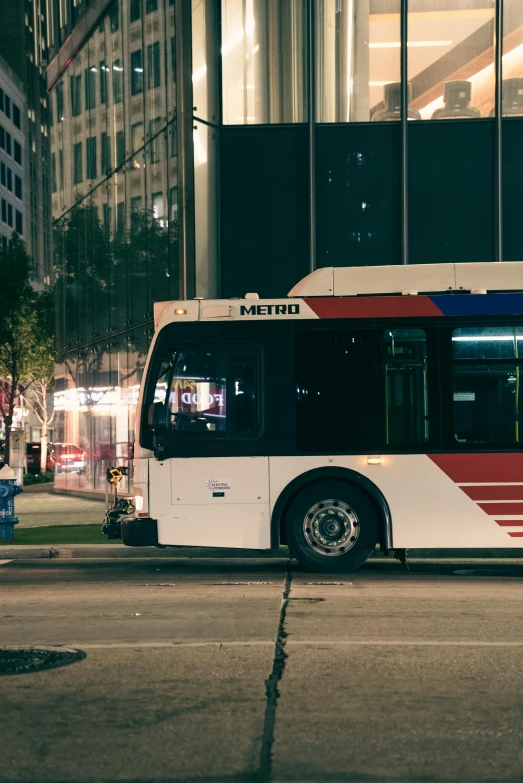 a white city bus with red, blue and white stripes