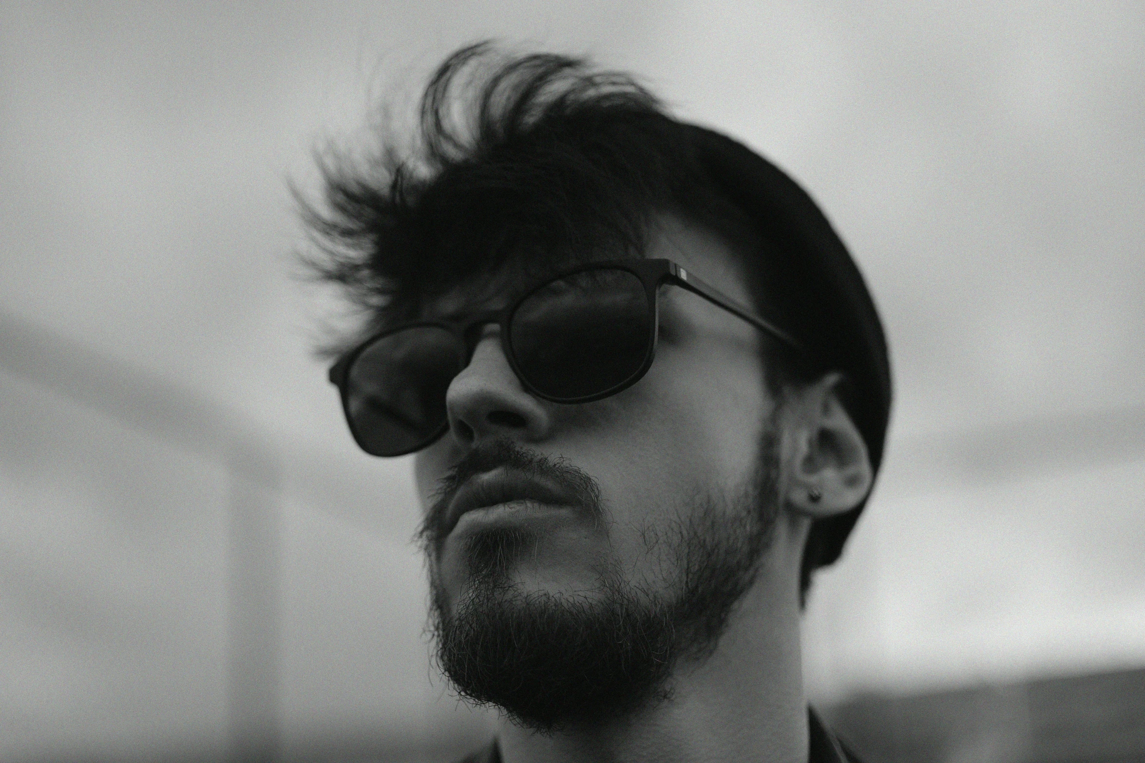 a man in sunglasses looking up while wearing a collared shirt