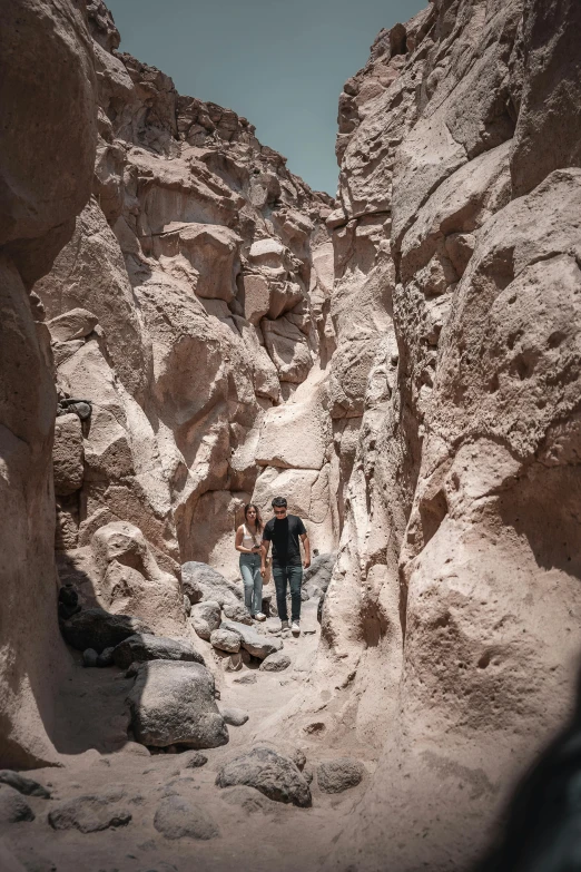 three people are hiking between rocks and dry vegetation