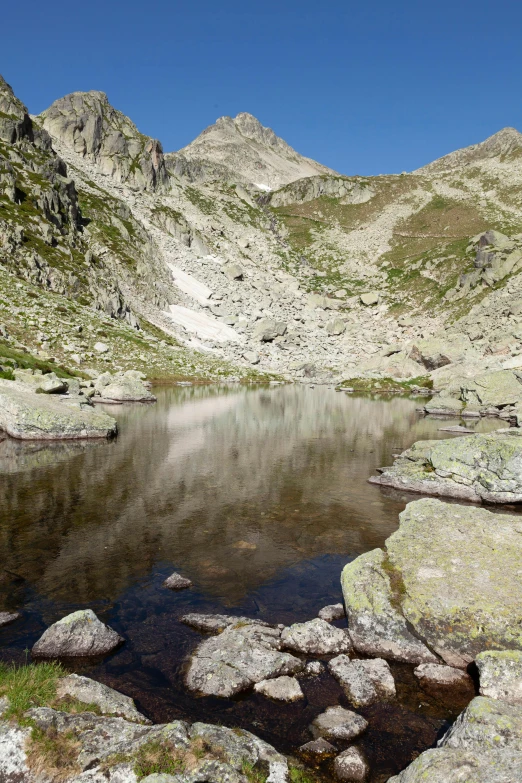 a lake surrounded by some mountains under a blue sky