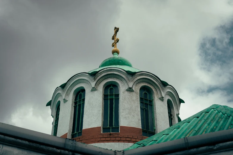 the top of an old church that is green and white