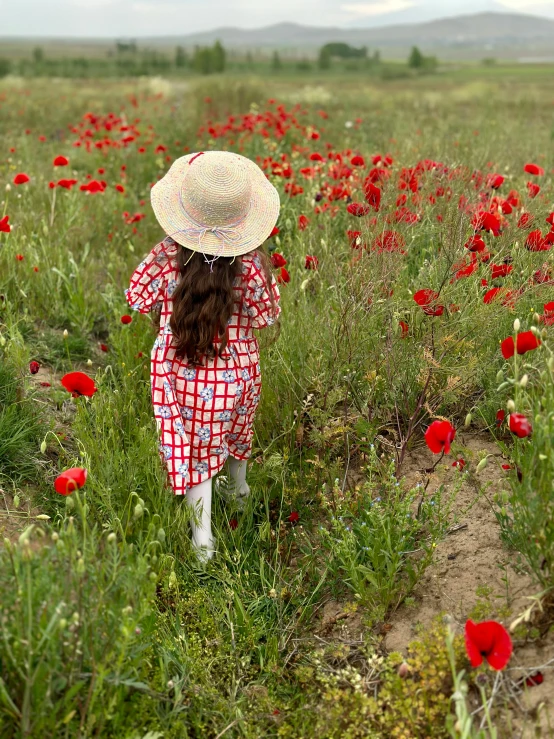 a woman standing in a field with a hat on her head