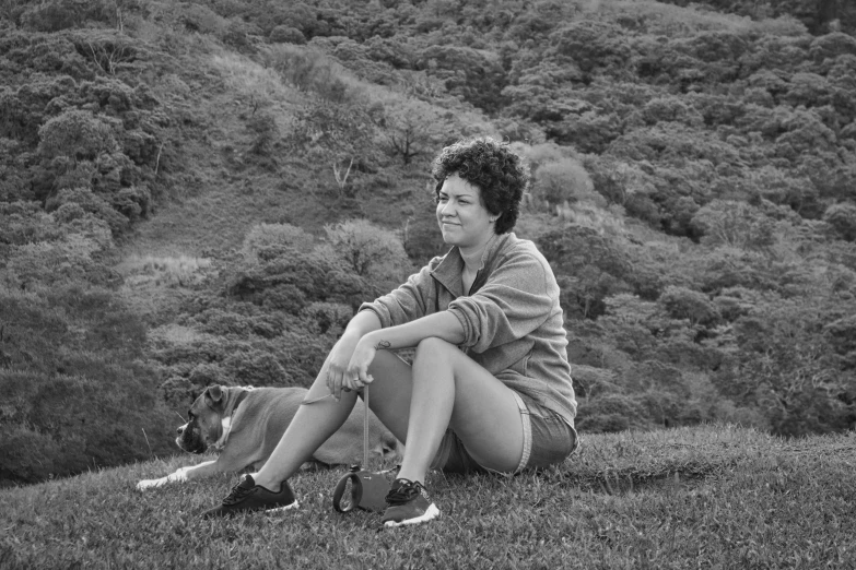 a woman sitting in a field with a dog