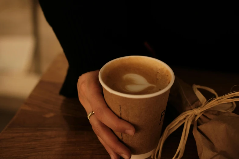 a cup of coffee with a heart shaped foam is held by the hands